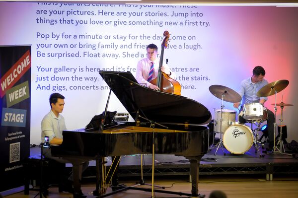 Jazz musicians play a grand piano, cello and drums.