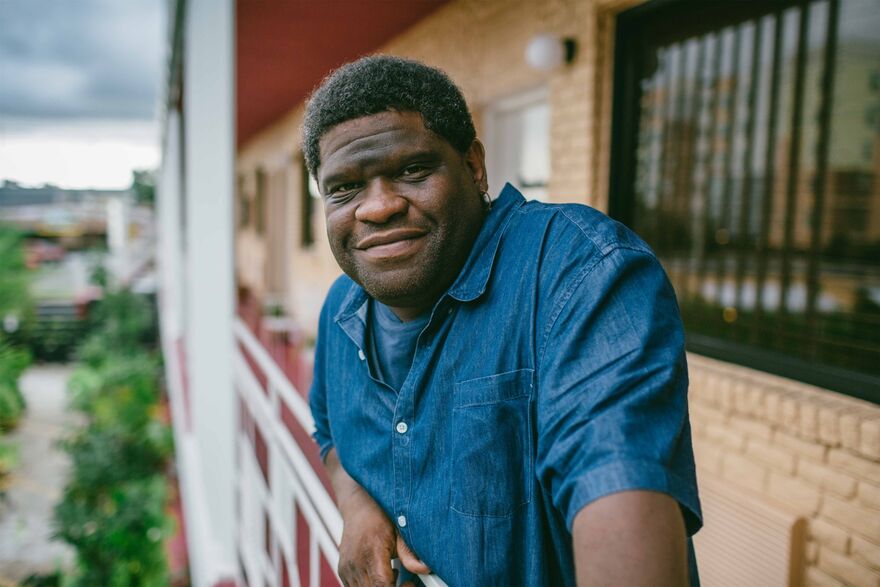 Gary Younge in a blue denim shirt leaning over a balciny