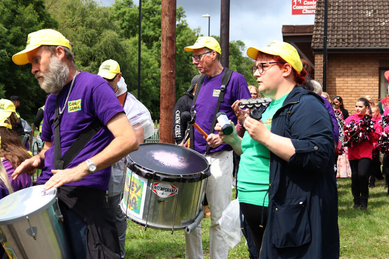 Members of the Canley Samba band perform during the Canley Parade, dressed in matching purple t-shirts and yellow caps.