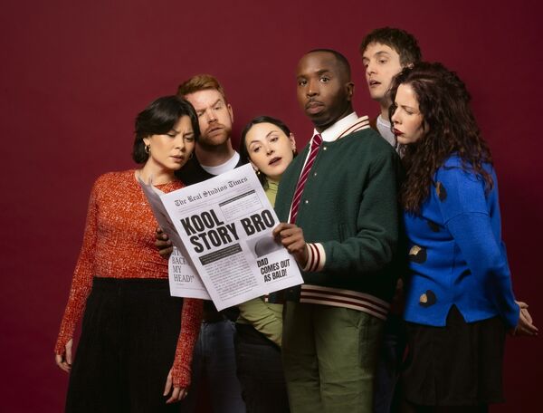 Kiell Smith Bynoe reading a newspaper surrounded by other actors also reading the same paper