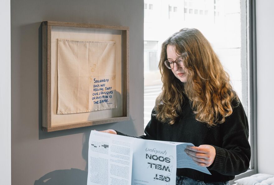 Person sat in a windowsill reading a newspaper