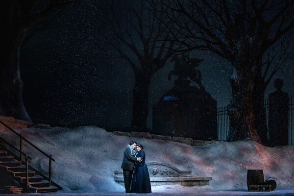 A couple embrace as it snows. 