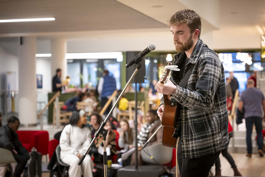 A guitar player singing into a microphone in front of an audience