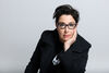 Sue Perkins in all black with one hand on face