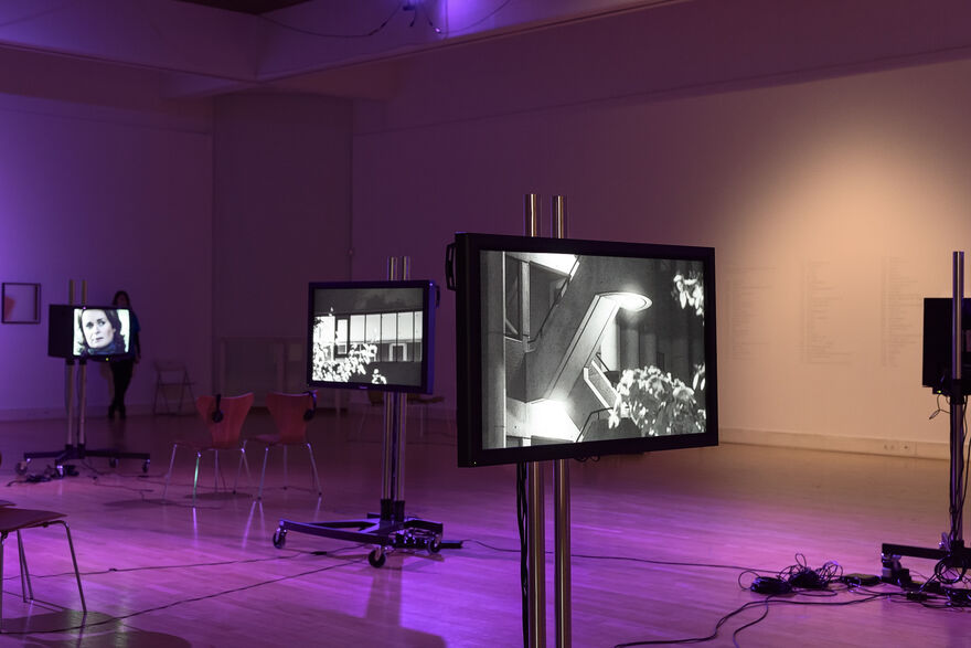 TV screens with black and white images in, bathed in purple light