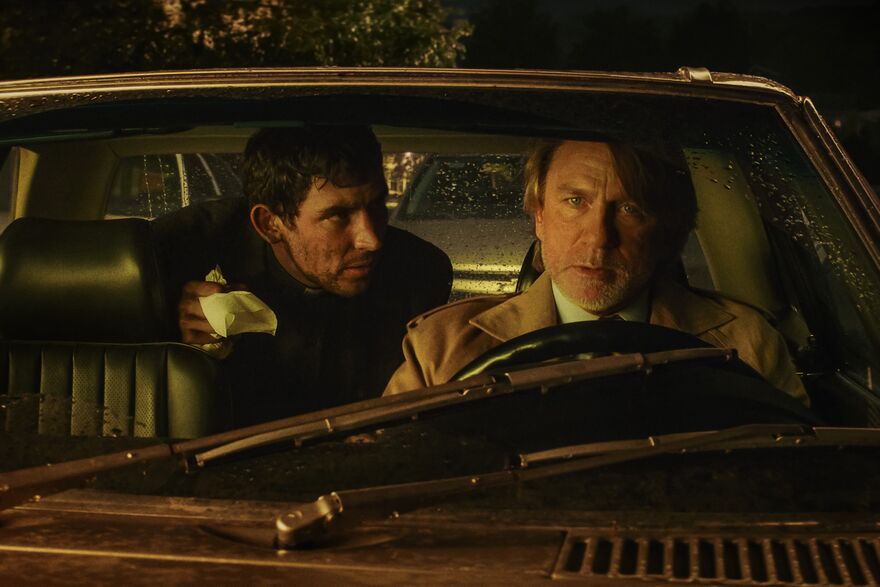 Daniel Craig and Josh O'Connor sat in a car