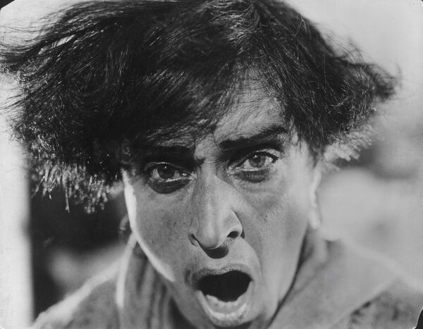 A black and white image of a man with his mouth open and eyes wide. 