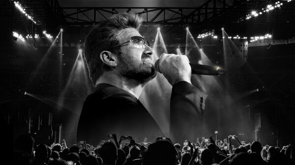 George Michael tribute artist Rob Lamberti performing with a microphone under dramatic concert spotlight beams.