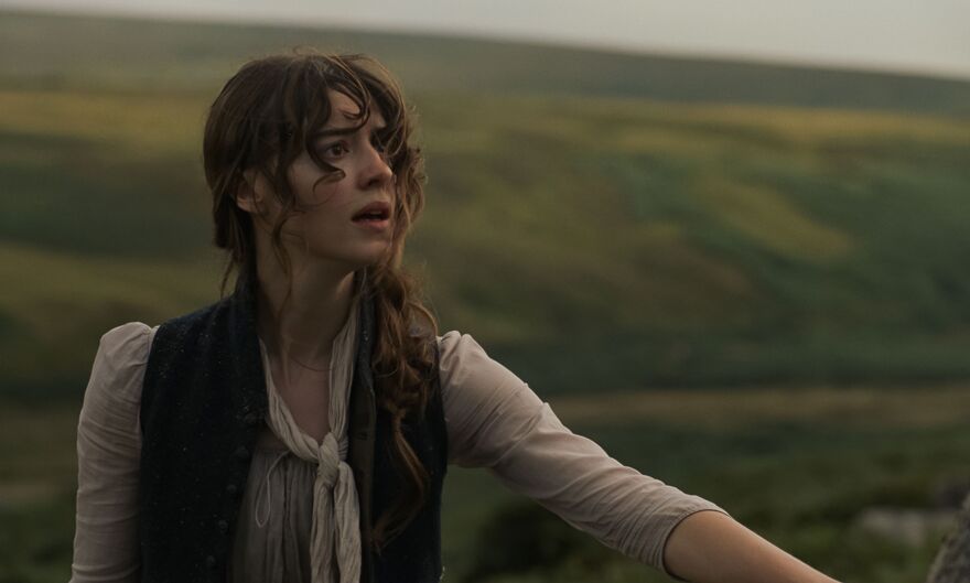 A young woman stands in a field. 