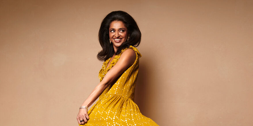 Sindhu Vee in a yellow dress against a pale brown background