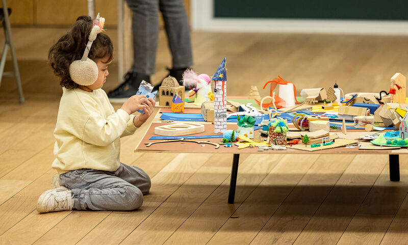 Child kneeling on the floor playing with paper crafts