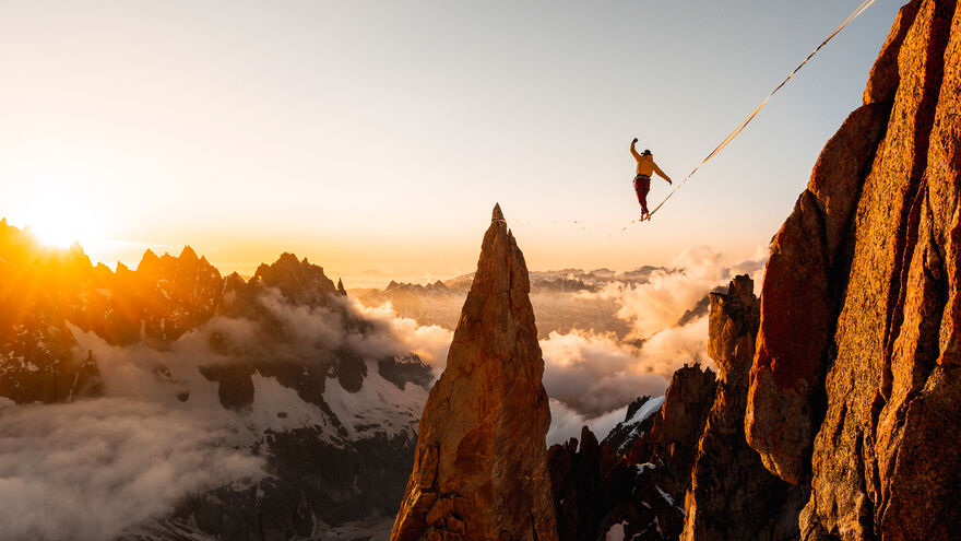Mountains with someone walking on a tightrope above the clouds