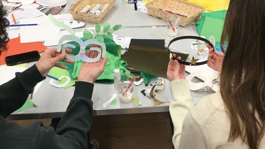 Participants displaying handmade paper masks and craft materials during a creative workshop.