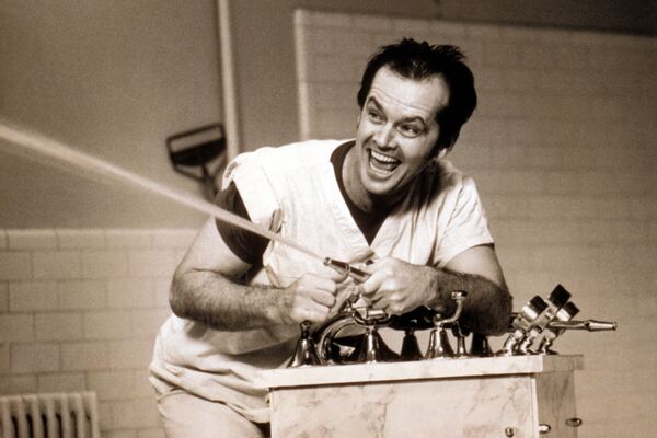 Jack Nicholson spraying water from a hose with a big smile on his face