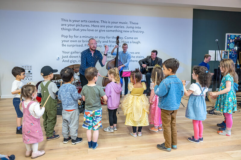 Children standing around a live band performing