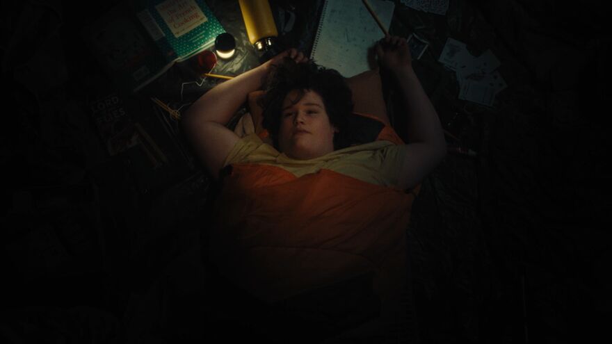 A boy lies in a sleeping bag looking up.