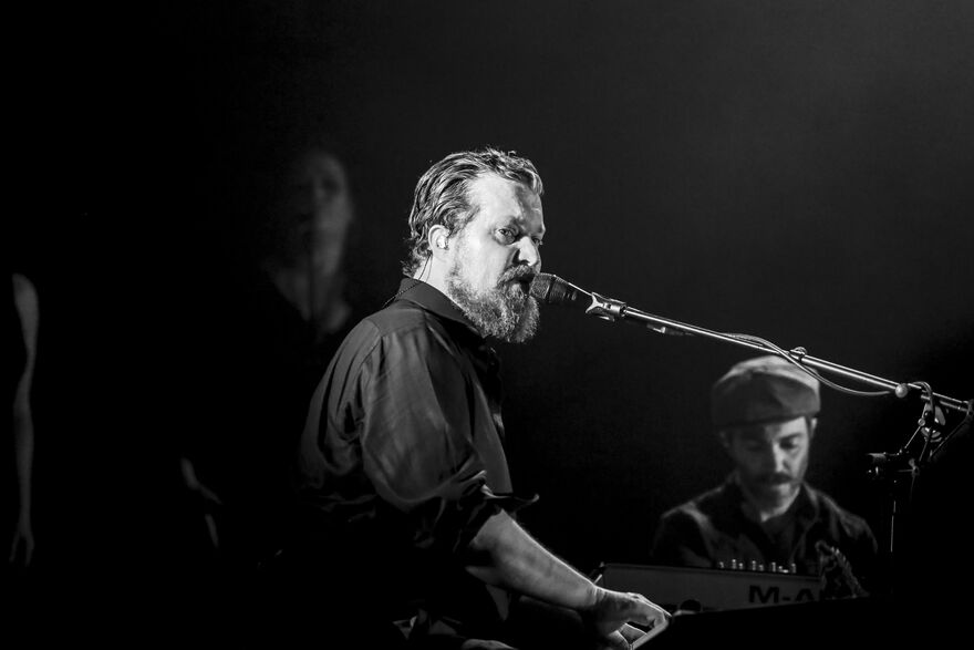 John Grant playing piano and singing into a microphone