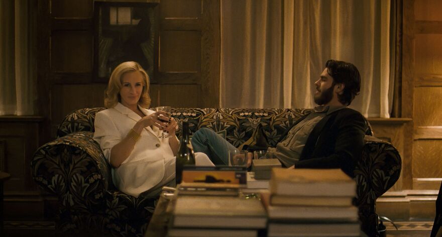 An older woman and younger man sit opposite each other on a sofa. 