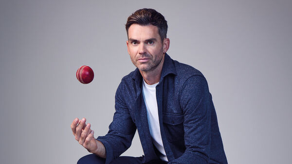 Jimmy Anderson in a navy blue shirt and white t-shirt  throwing a cricket ball