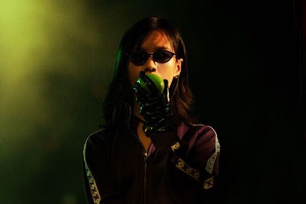 A woman wearing sunglasses bites into a green apple. 