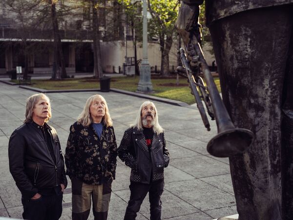 The members of Spinal Tap look up at a statue.