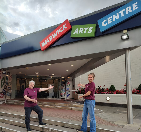 Two volunteers standing outside the entrance to Warwick Arts Centre