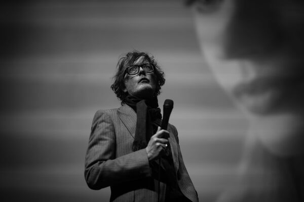 A black and white photo of Jarvis Cocker holding a mic. A black and white photo of Jarvis Cocker holding a mic.