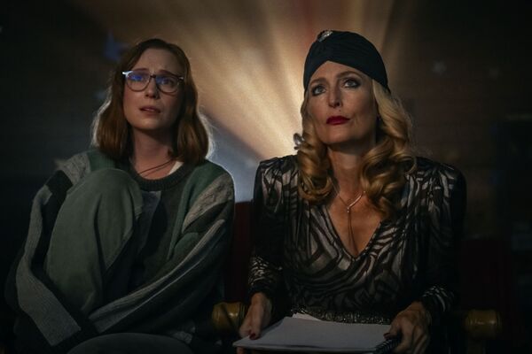 Two women watching a film. The younger woman wears leisure clothing whilst the older woman wears old Hollywood glamour. Two women watching a film. The younger woman wears leisure clothing whilst the older woman wears old Hollywood glamour.