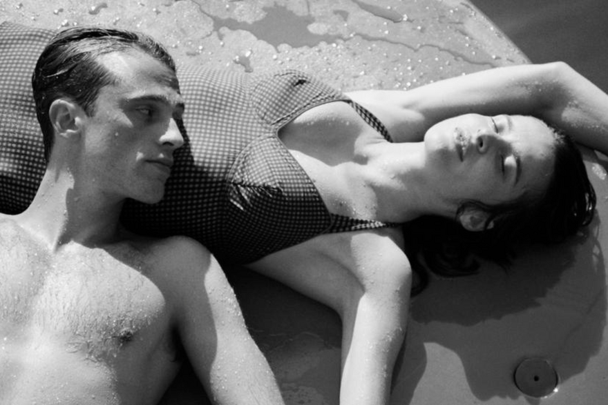 Black and white image of a man resting his head on a womans stomach, both are laying down