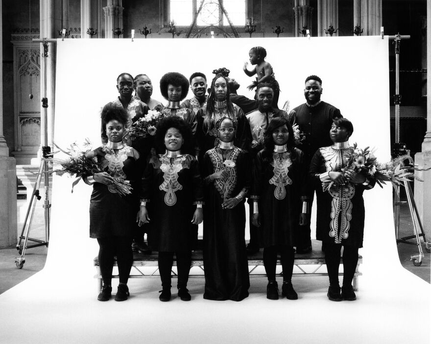 A group of people stand in front of a white background