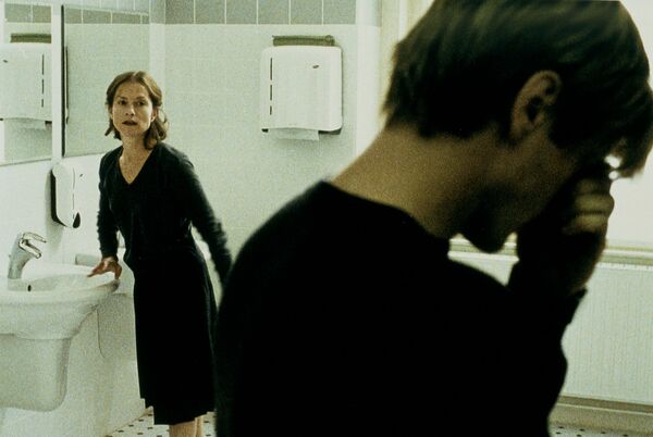 A woman stands against a bathroom sink looking over a man with his head in his hands. 