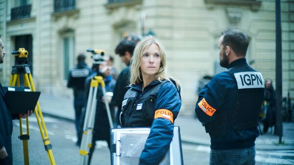A female police officer stands with a clipboard at a crime scene. 