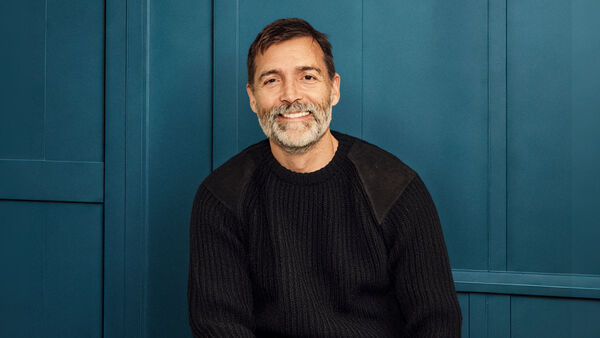 Patrick smiles at the camera in front of a blue background 
