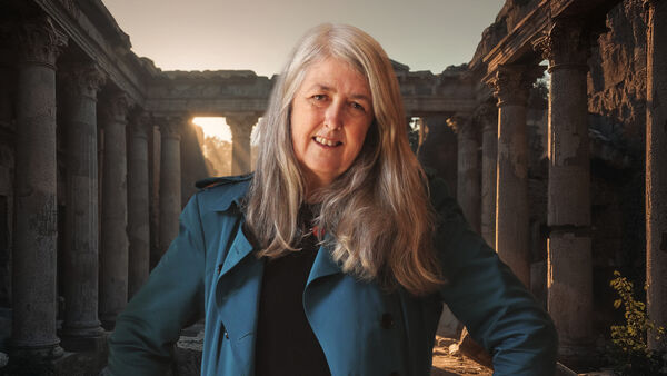 Mary Beard smiling with roman ruins behind her
