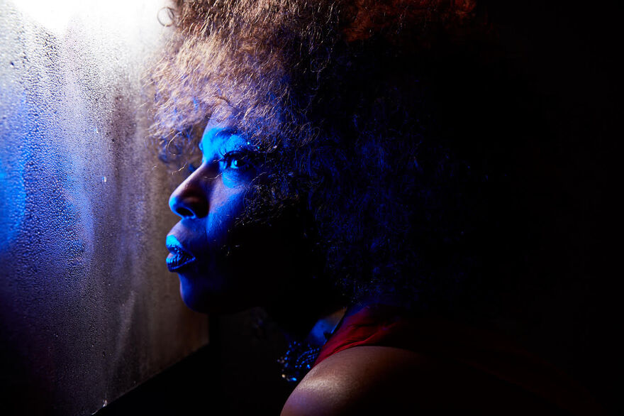 Close up of Macy Gray looking out a steamy window with a blue light on her face