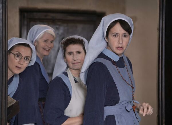 A group of nuns peer into a room. 