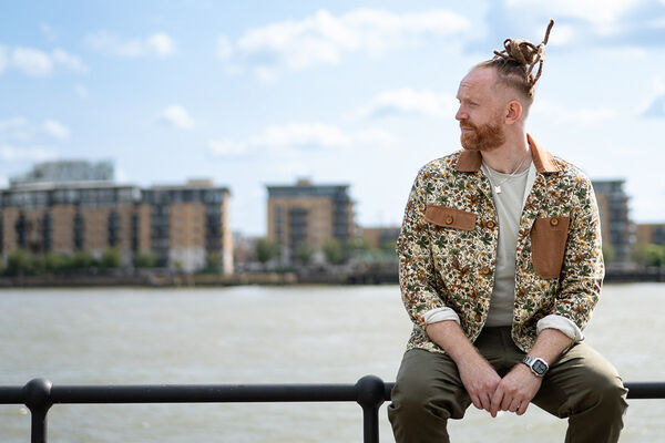 Newton Faulkner  sitting on a railing next to a river