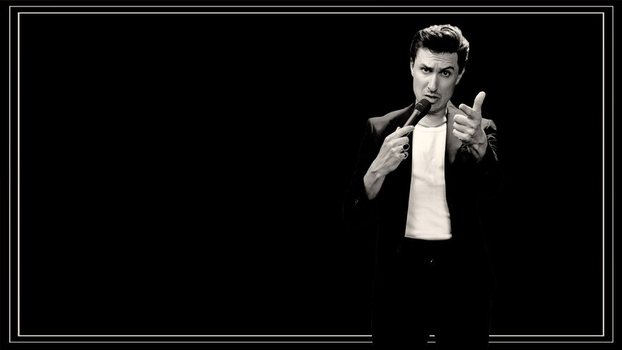 Tom Rosenthal holding a microphone, image in black and white