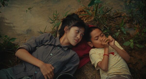 A young woman lies on the ground beside a young child. 