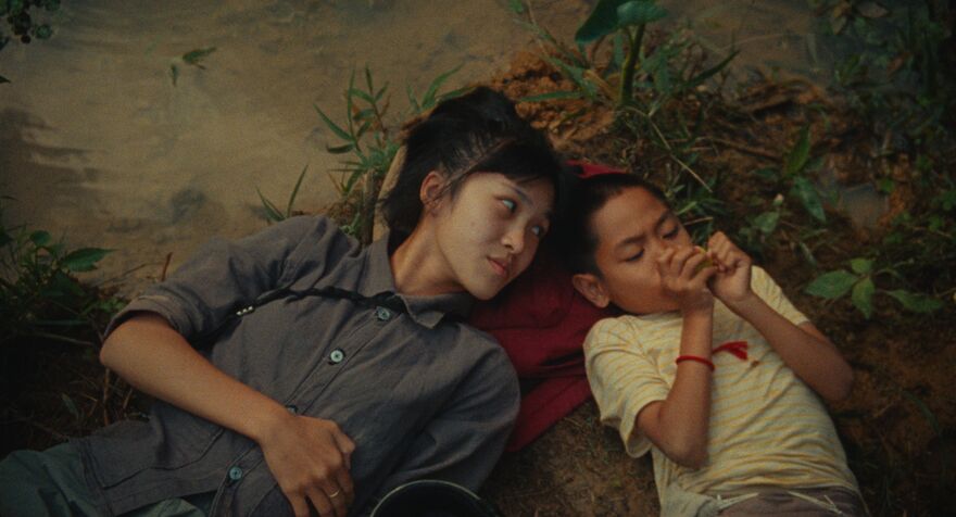 A young woman lies on the ground beside a young child.