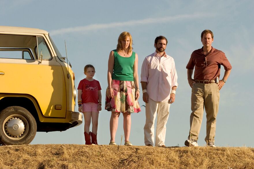 A family stand on the side of a road next to a yellow van. 