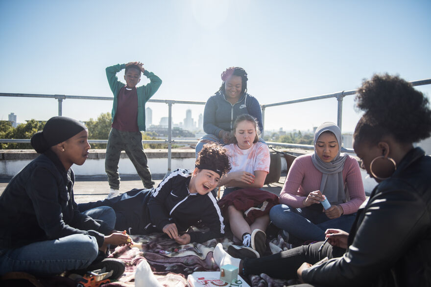 A group of teenage girls sit together on a rooftop