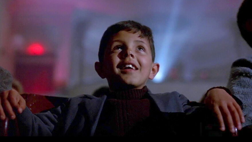 Young boy sat in a cinema looking upwards joyfully