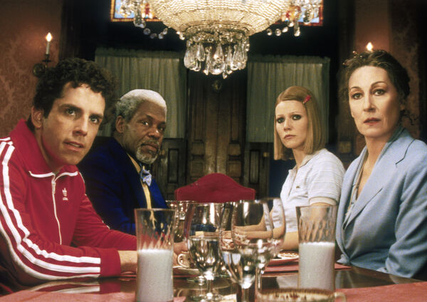 A group of four sit around a dinner table staring towards the camera. 