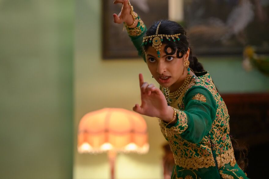 Woman in green and gold decorative tunic, holding her hands up in a martial arts stance