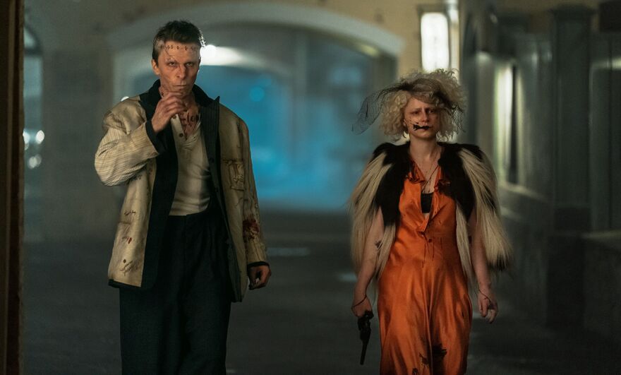 Christian Bale as Frankenstein and Jessie Buckley as The Bride walk down a street. 