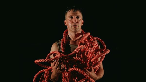 A man with a long red rope around his shoulders and neck