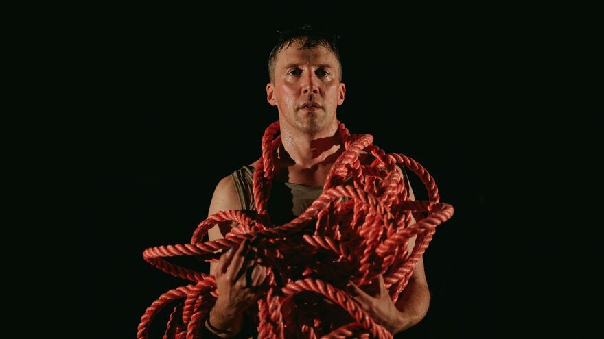 A man with a long red rope around his shoulders and neck