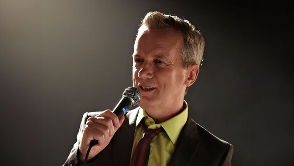 Frank Skinner in a suit holding a microphone 