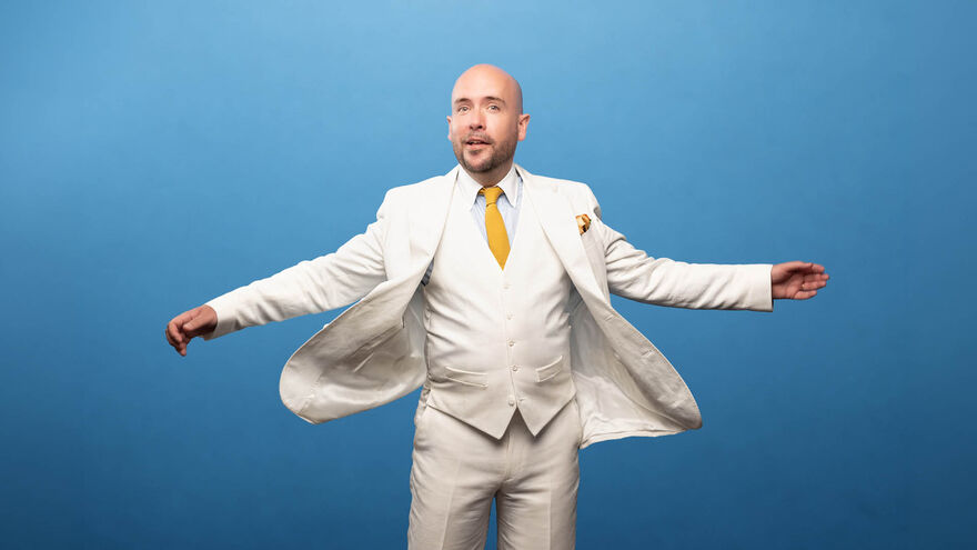 Tom Allen in a white suit with a blue background